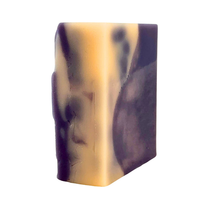 Bar of soap with a marbled pattern of purple and yellow on a white background