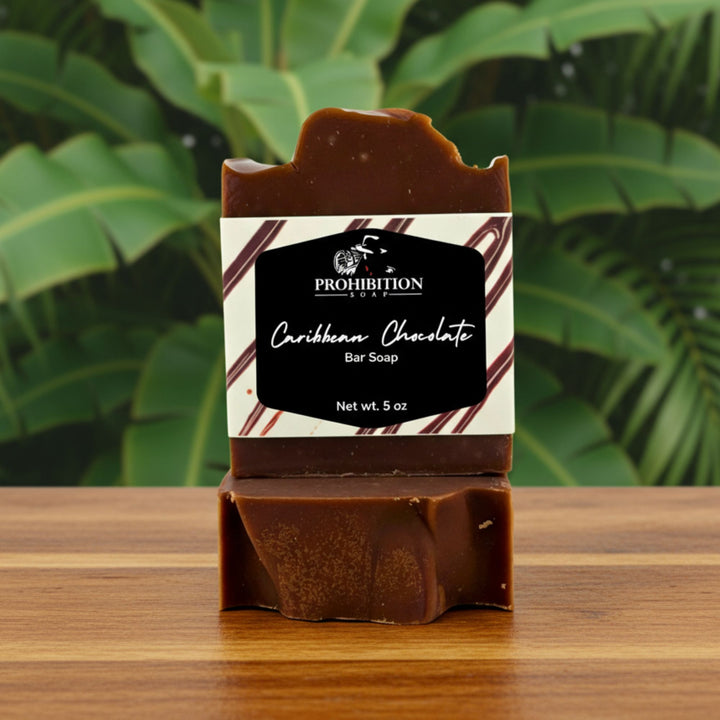 Bar of Caribbean Chocolate soap with packaging on a wooden surface and green leafy background