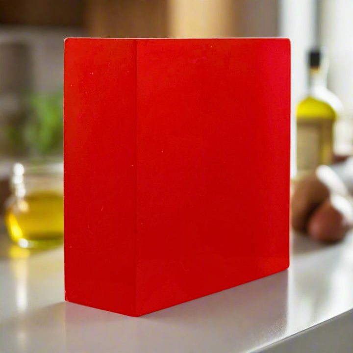 Red rectangular soap on a kitchen counter with blurred background
