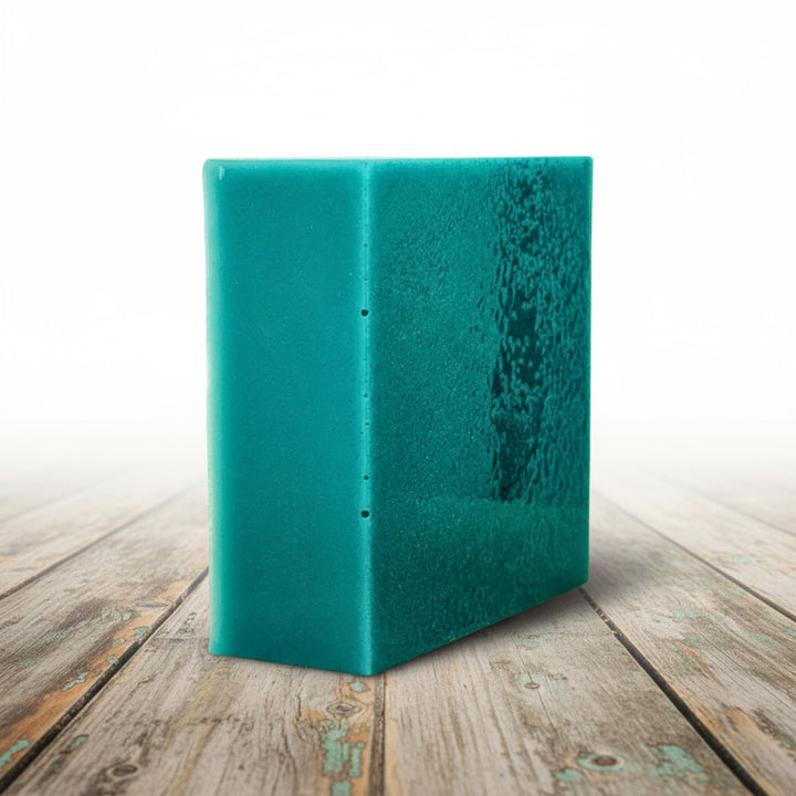 Teal soap on a wooden surface with a white background