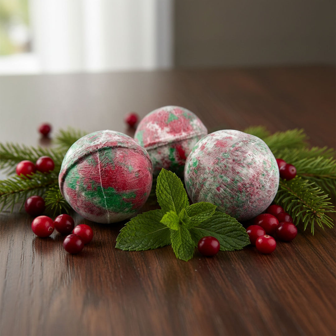 Bath bombs with a festive design surrounded by berries and mint leaves on a wooden surface.