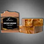 Kentucky Bourbon bar soap with label alongside two unwrapped bars showing swirled amber soap, on a gray gradient background