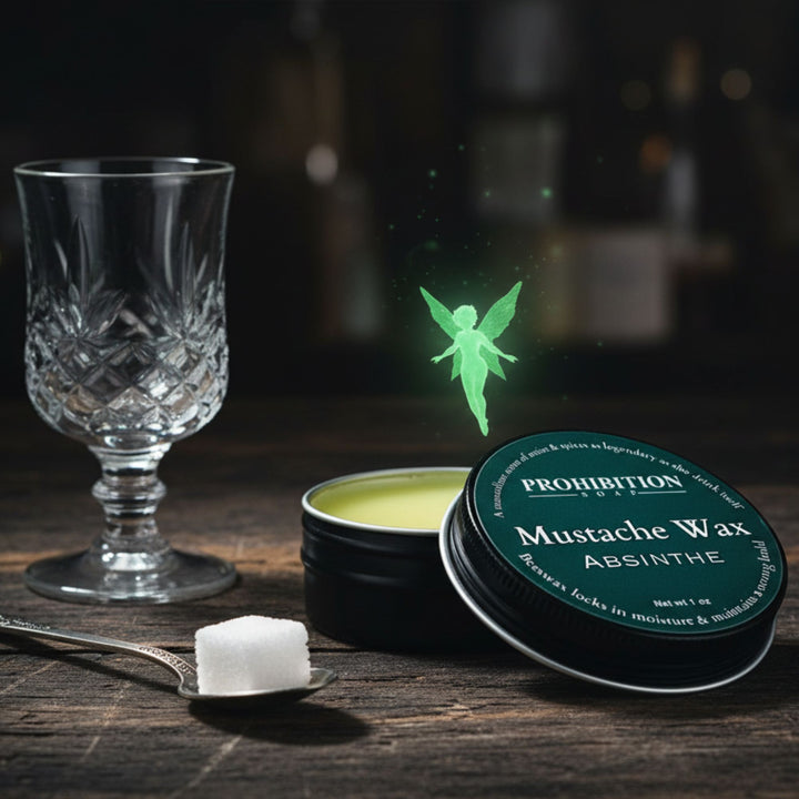 Mustache wax container labeled 'Prohibition Products Absinthe' with a glass and spoon on a wooden surface.