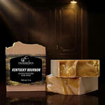 Kentucky Bourbon bar soap with label standing upright beside two unwrapped bars stacked on a dark reflective surface, with a dimly lit speakeasy door in the background
