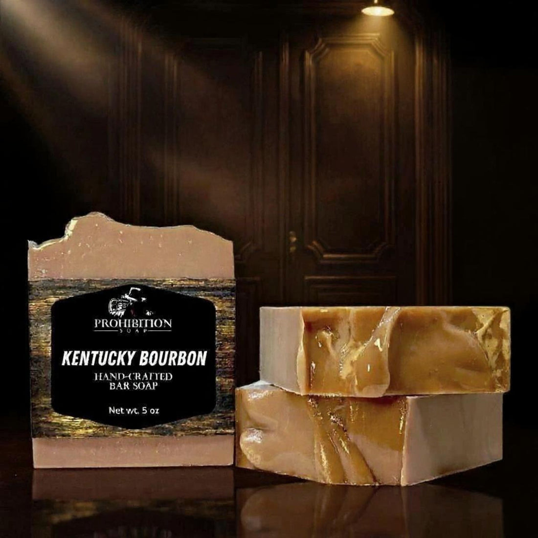 Kentucky Bourbon bar soap with label standing upright beside two unwrapped bars stacked on a dark reflective surface, with a dimly lit speakeasy door in the background