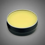 Round container with a golden balm on a gray background