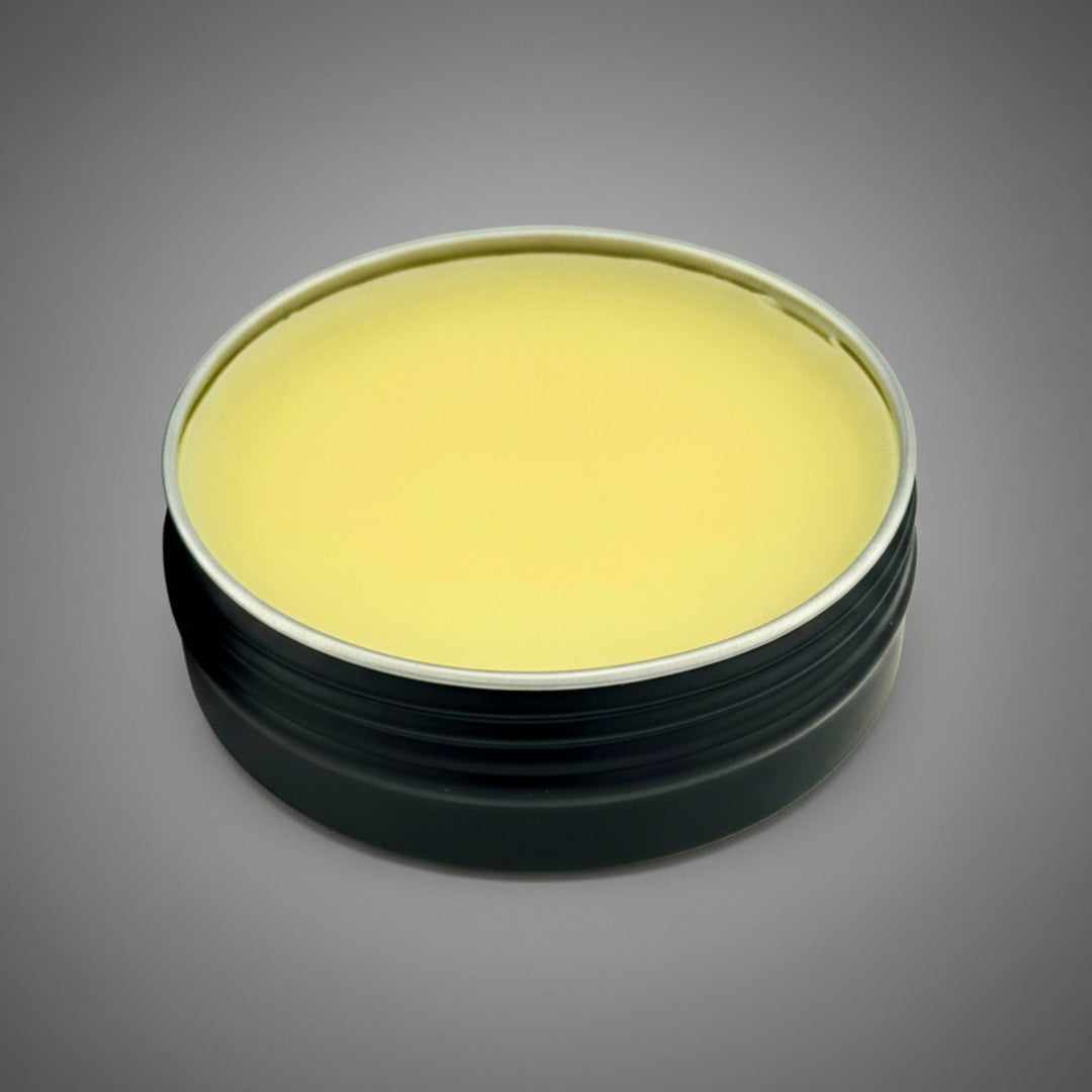 Round container with a golden balm on a gray background