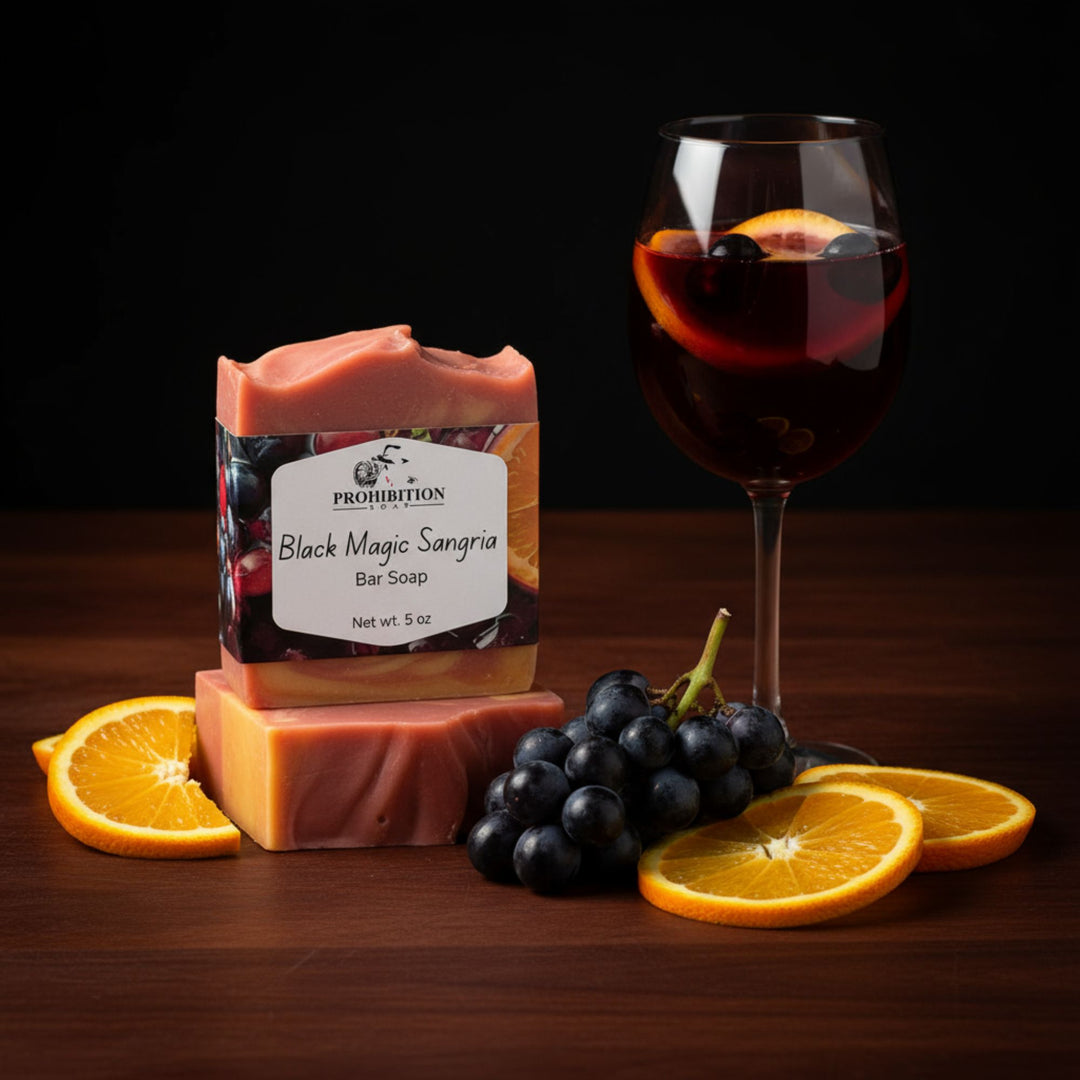 Black magic sangria bar soap next to oranges and grapes with wine on a wooden table top