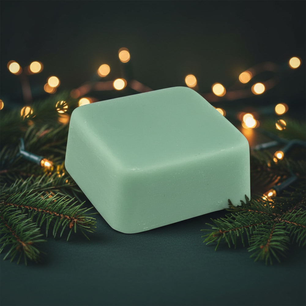Green wax melt on a dark surface with blurred lights and greenery in the background