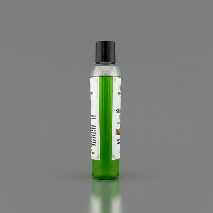 A clear plastic bottle filled with bright green gel, featuring a black cap and a white label, standing upright on a reflective gray surface against a solid gray background.