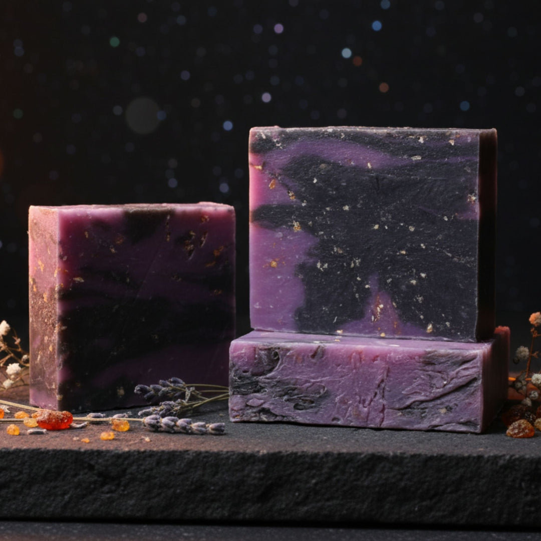 Three purple soap bars with natural elements on a dark background