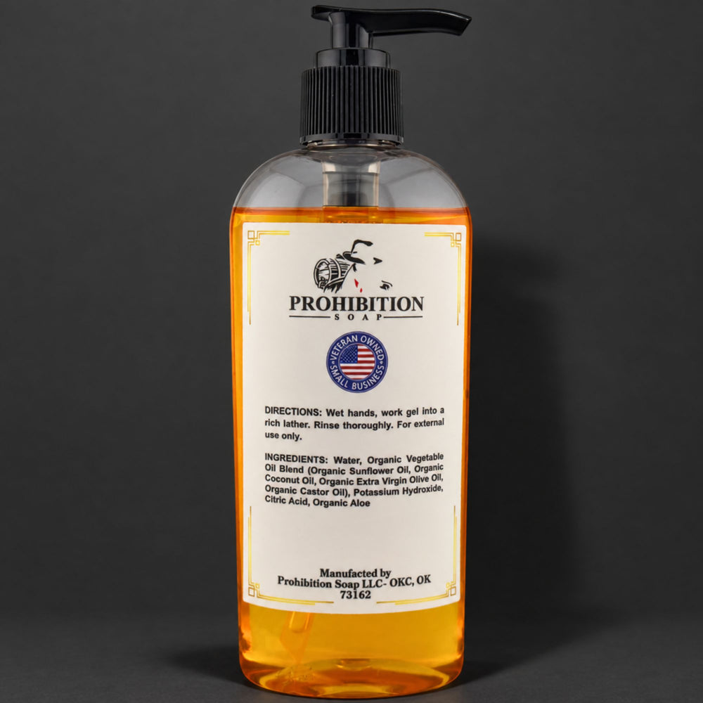 A clear plastic pump bottle of Prohibition Soap hand soap with amber-colored liquid inside, featuring a white label with black text and logo, set against a dark gray background.