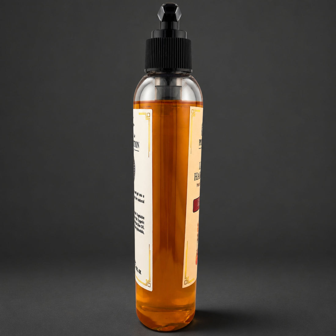 A clear plastic bottle filled with amber-colored soap, featuring a black dropper-style cap and cream-colored labels, set against a dark gray background.