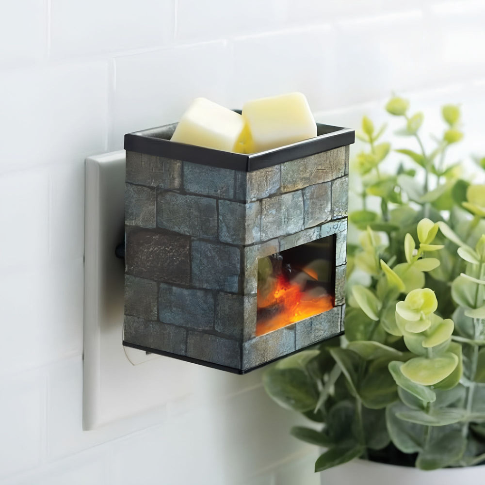 Wall-mounted decorative fireplace fragrance warmer with glowing interior, featuring a plant in the foreground.