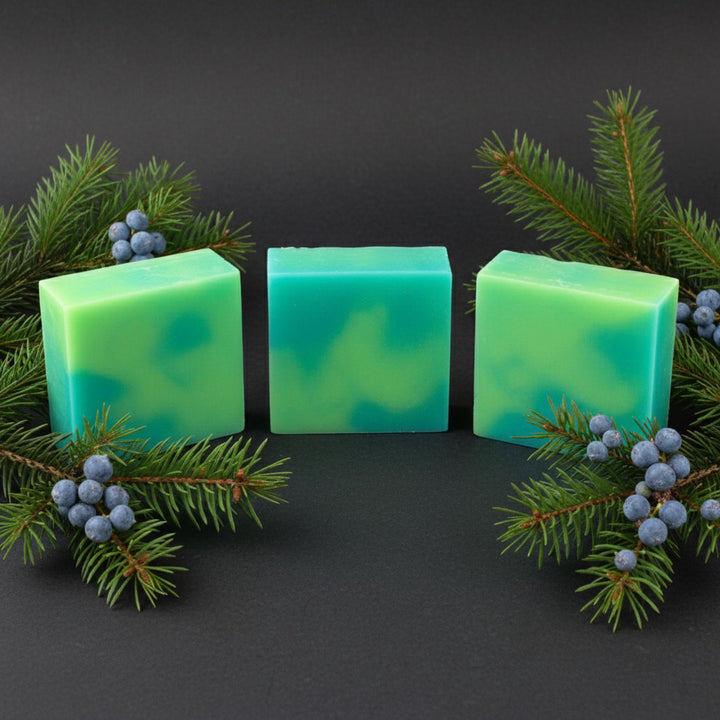 Three green soap bars with a dark background and greenery
