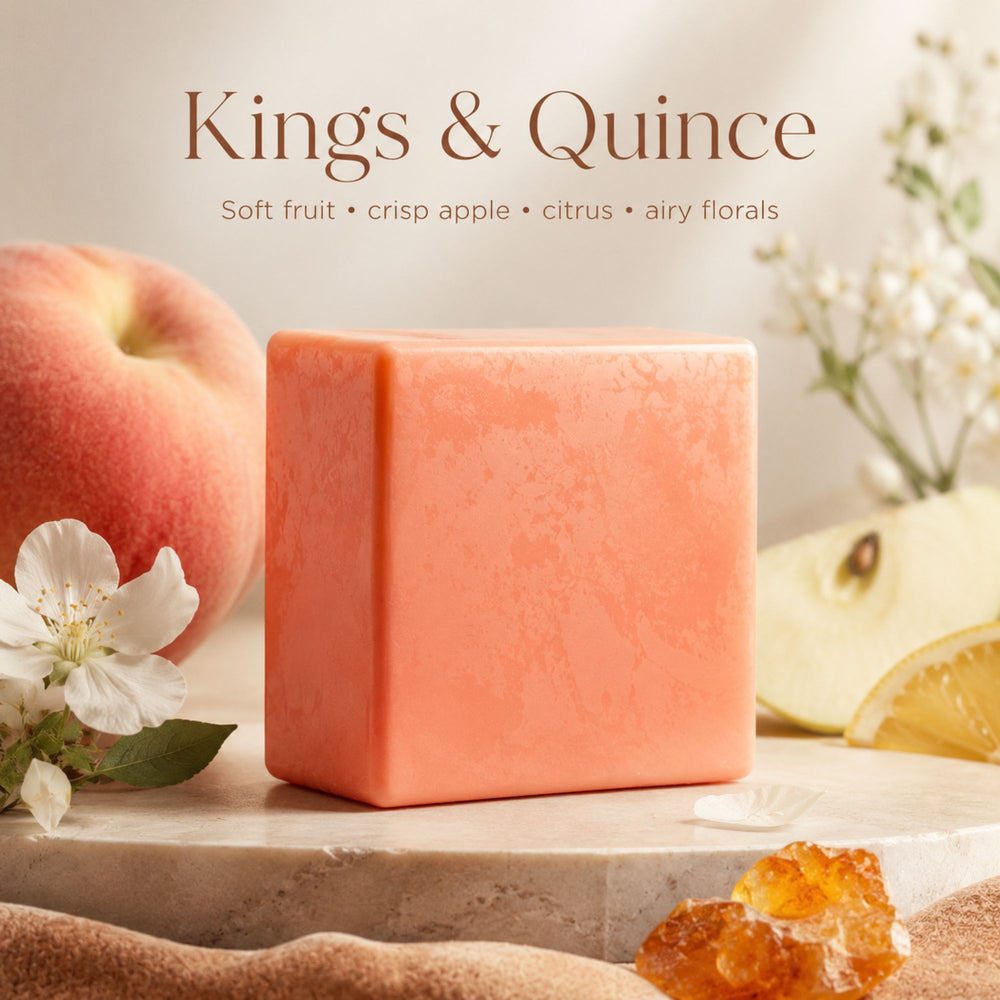 Bar of soap with 'Kings & Quince' branding, surrounded by fruits and flowers on a light background.