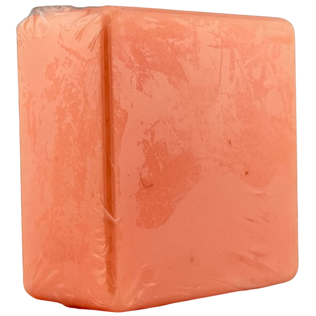 Block of orange soap with a clear plastic wrap on a white background