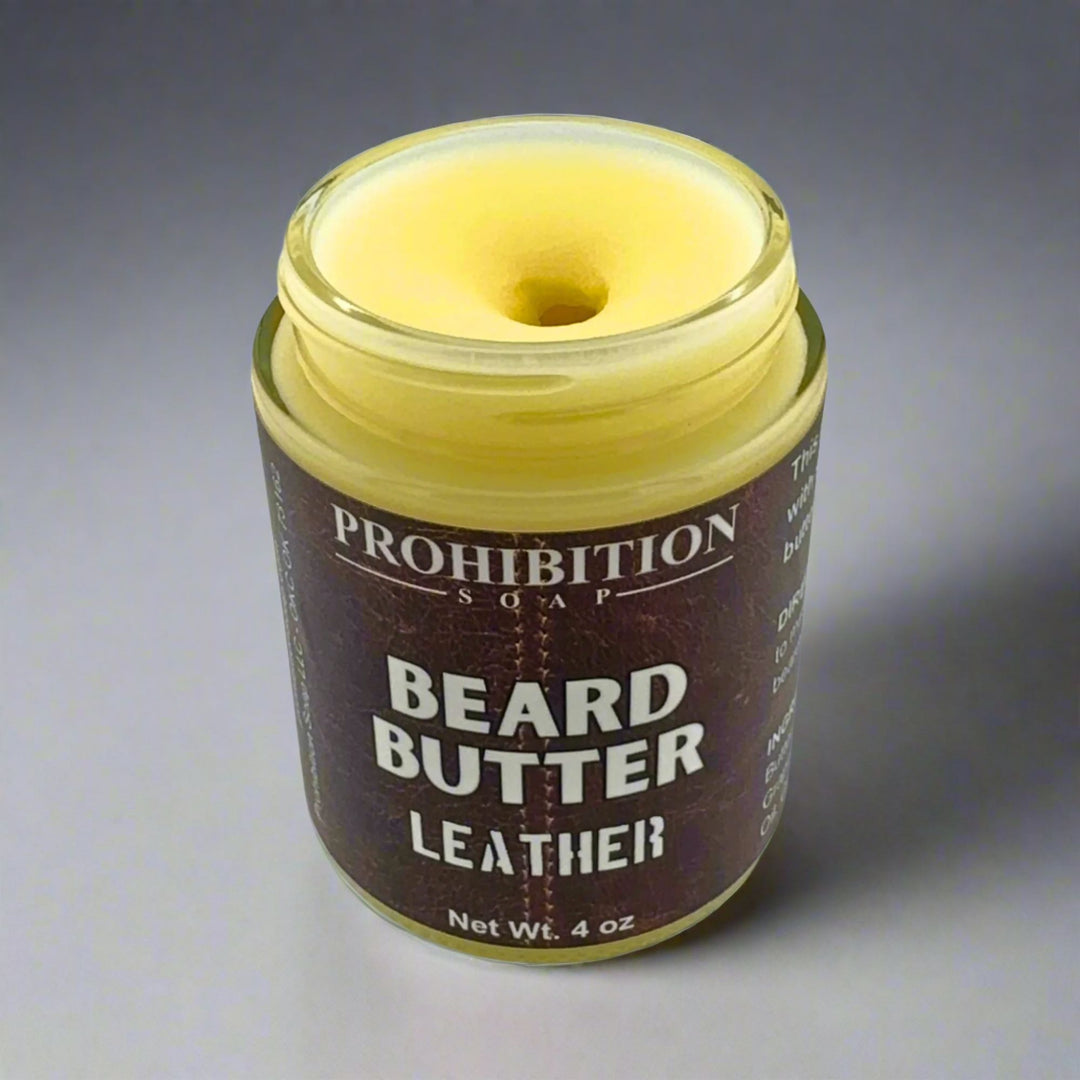 Prohibition Soap Beard Butter in Leather scent - open 4 oz glass jar showing rich golden butter texture and consistency with leather-textured brown label on gray background
