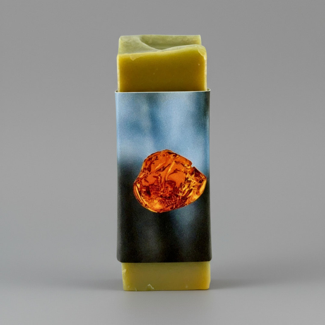 Bar of soap with a decorative label featuring an amber stone on a gray background
