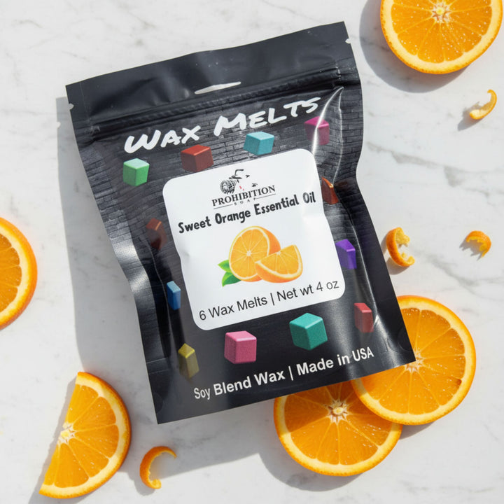 Packaging of Prohibition Soap Wax Melts with sweet orange essential oil, surrounded by sliced oranges on a light background.
