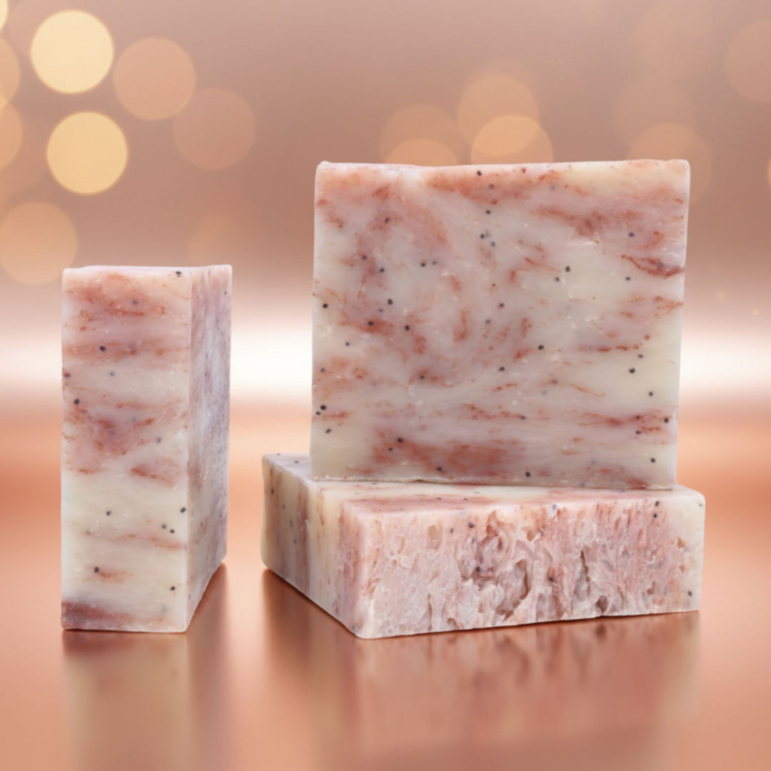 Three bars of marbled soap on a reflective surface with a blurred bokeh background