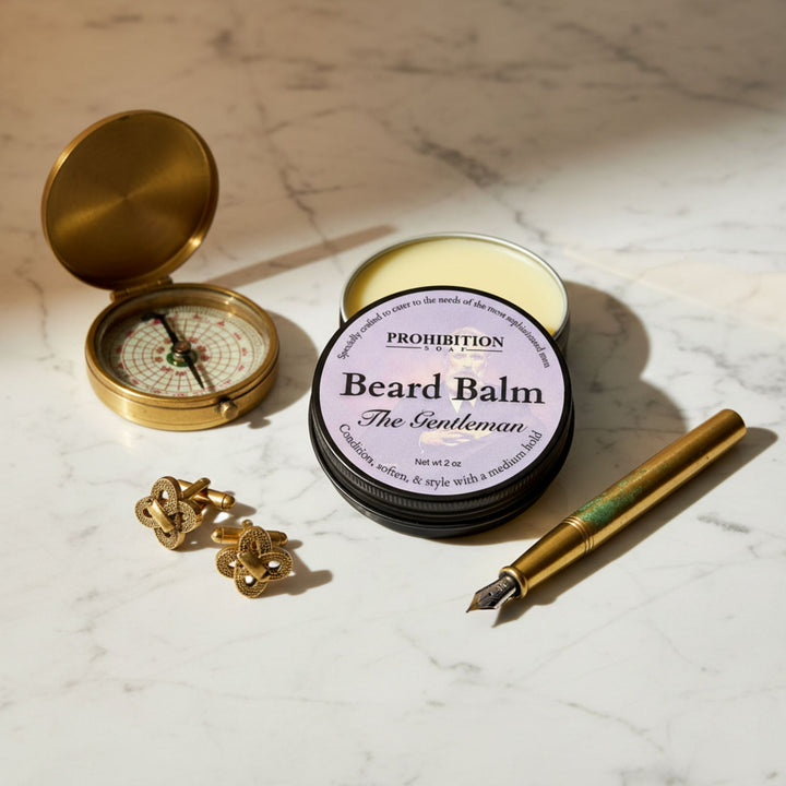 Beard balm container with a compass, pen, and cufflinks on a marble surface