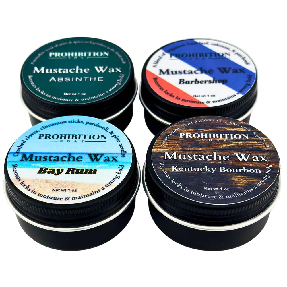 Five tins of Prohibition Soap Company mustache wax with different flavors on a white background.