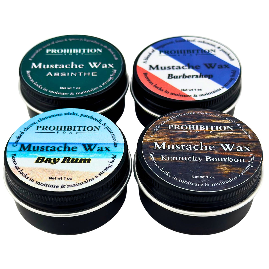 Five tins of Prohibition Soap Company mustache wax with different flavors on a white background.